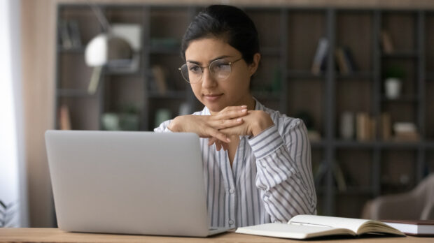 woman wearing glasses and looking at a laptop